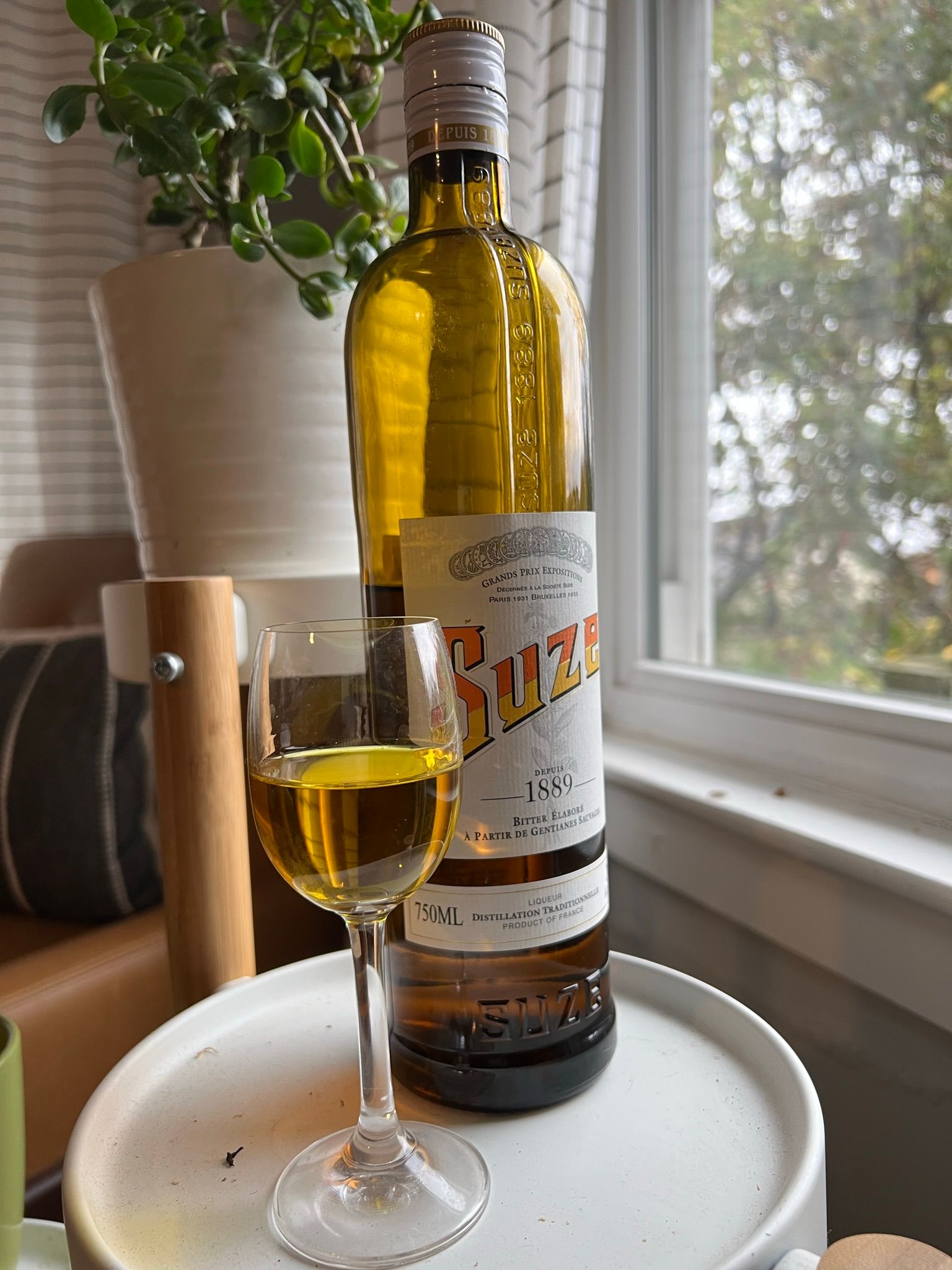 A photo of a bottle of Suze alongside a small glass of Suze.